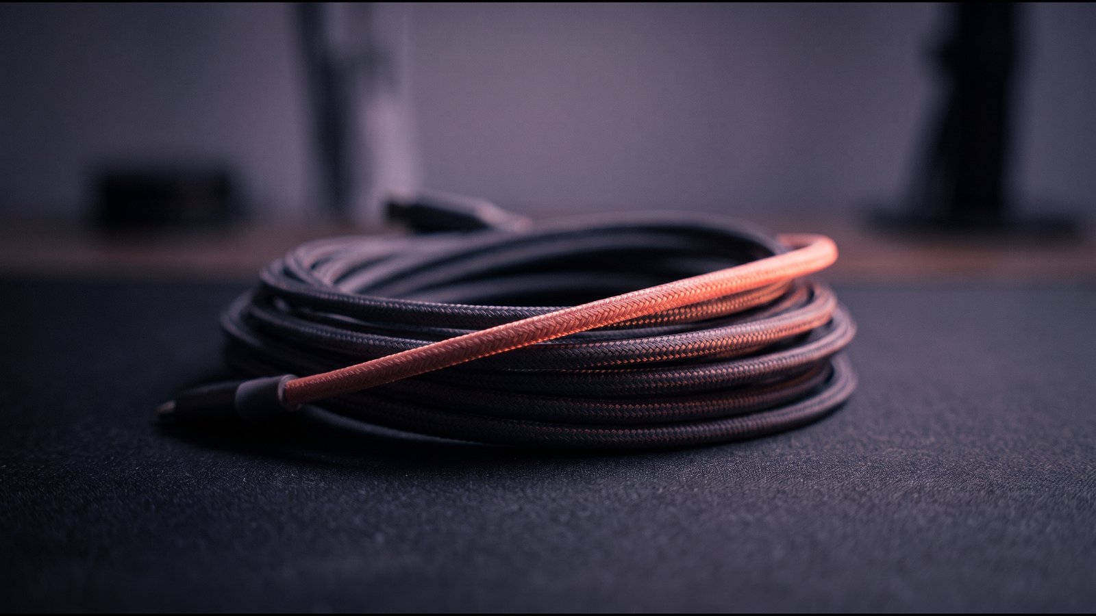 Neatly coiled pale cables on a white surface, one strand in warm light