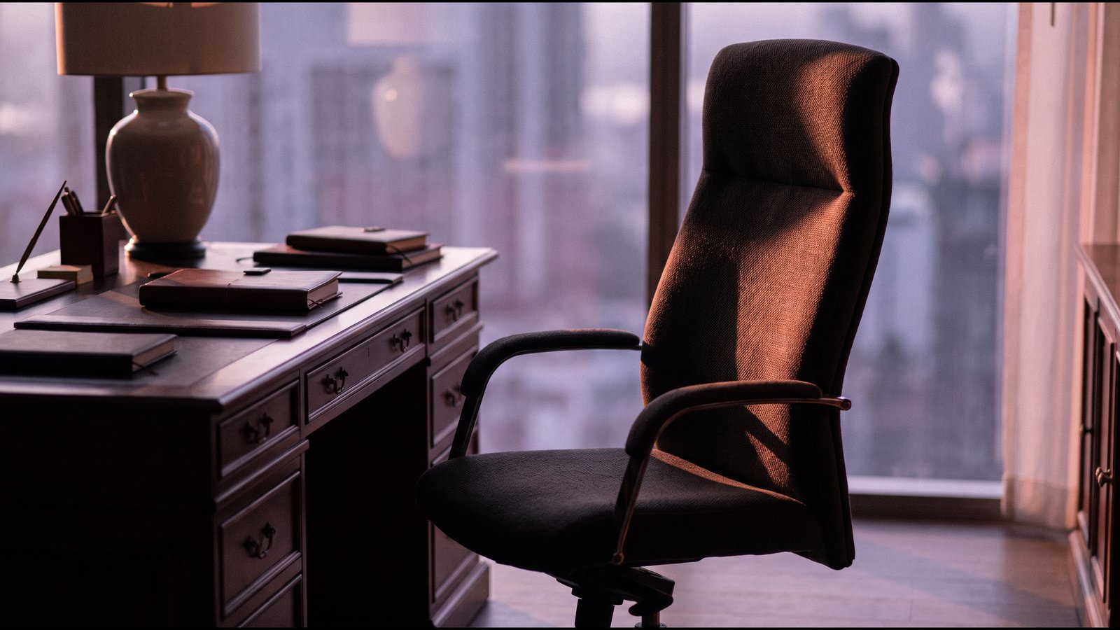 An empty chair pushed back from a plain table in soft window light